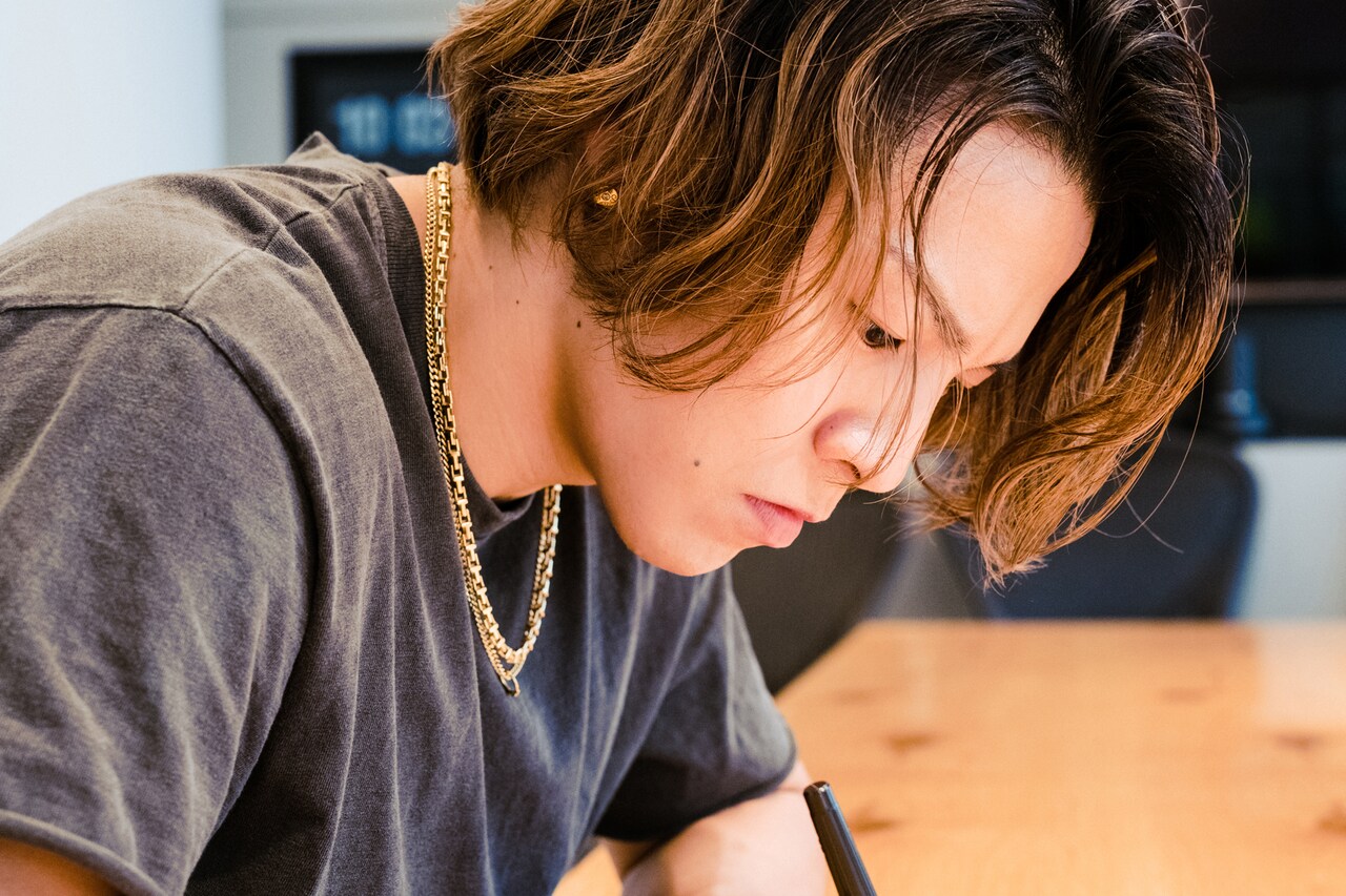 真剣な眼差しでスケッチブックに筆を走らせるRIKUさん。