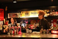 バーカウンターに立つ辛島菜摘（左）と綾小路翔（右）。