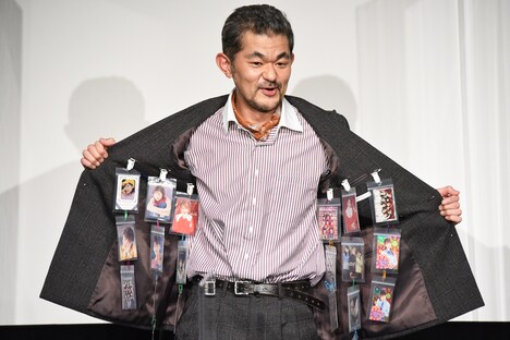 スーツの内側に仕込んでいたハロプロメンバーの写真を見せる芹澤興人。