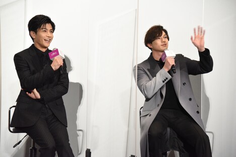 ムービーカメラに高速で手を振りアピールする新田真剣佑（右）。