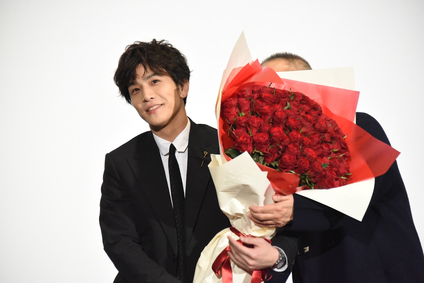 佐藤祐市監督と一緒にバラの花束を持つ岩田剛典。