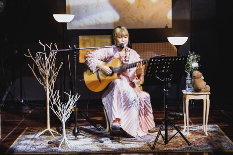 部屋のような空間でギターの弾き語りをするさとうもか。(Photo by nishinaga "saicho" isao)