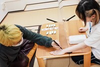 もしもしチャンの手に文字を書き入れる渡辺淳之介。