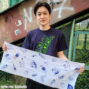 「ライブナタリー 手ぬぐい」を持つUK(MOROHA)。