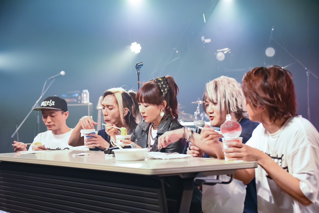 ライブ中にカップ麺を頬張るangelaとバンドメンバー。