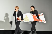 BLUE ENCOUNTの田邊駿一（Vo, G）のパネルを運ぶ04 Limited SazabysのGEN（B, Vo）とTHE ORAL CIGARETTESの山中拓也（Vo, G）。（Photo by AZUSA TAKADA）