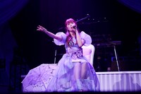 椅子に腰かけて歌う佐々木彩夏。