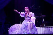 椅子に腰かけて歌う佐々木彩夏。