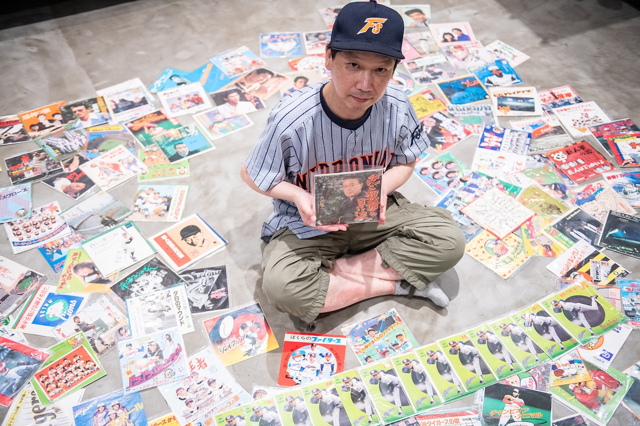 これまで集めてきた7inchの野球レコードに囲まれる中嶋勇二さん。