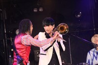 北原雅彦（Tb）のトロンボーンを手にする加藤隆志（G）。（写真提供：Sony Music Artists）