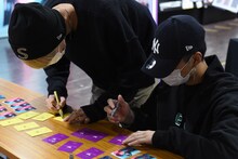 特典フォトカードにサインをする浦野秀太と中川勝就。