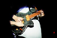 朝日（G）のギターと、左から伸びるもっさ（Vo, G）の手。（撮影：橋本塁）