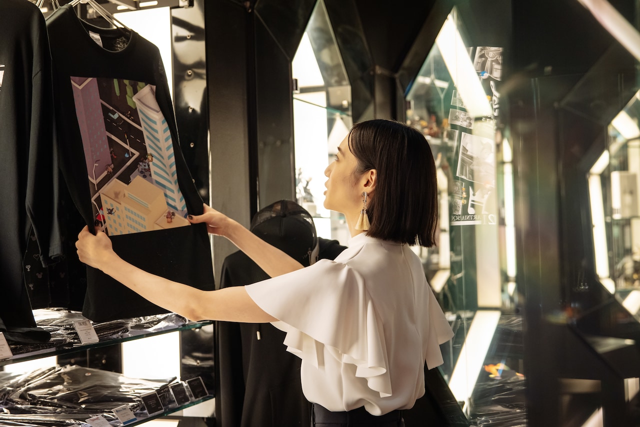 「ドラゴンクエストウォーク」のTシャツを手に取るのっちさん。