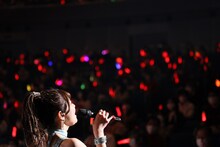 赤いペンライトの光に包まれながら歌唱する金澤朋子。