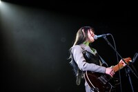 ギターを弾きながら歌うminan。