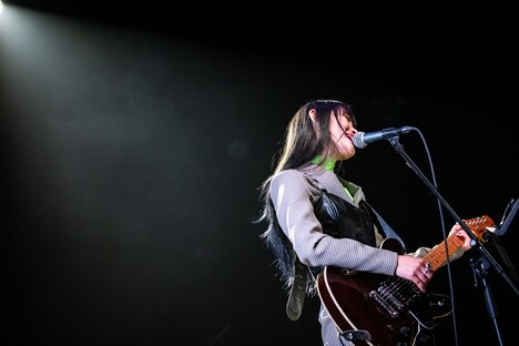 ギターを弾きながら歌うminan。