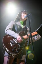 ギターを弾きながら歌うminan。