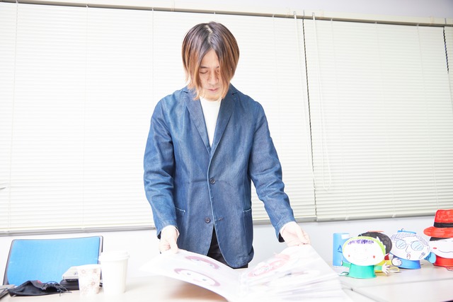 番組で使用した小物を見せてくれた和賀氏。右に見えるのは「サウンドランナー」で使用した紙人形。（撮影：梅原渉）