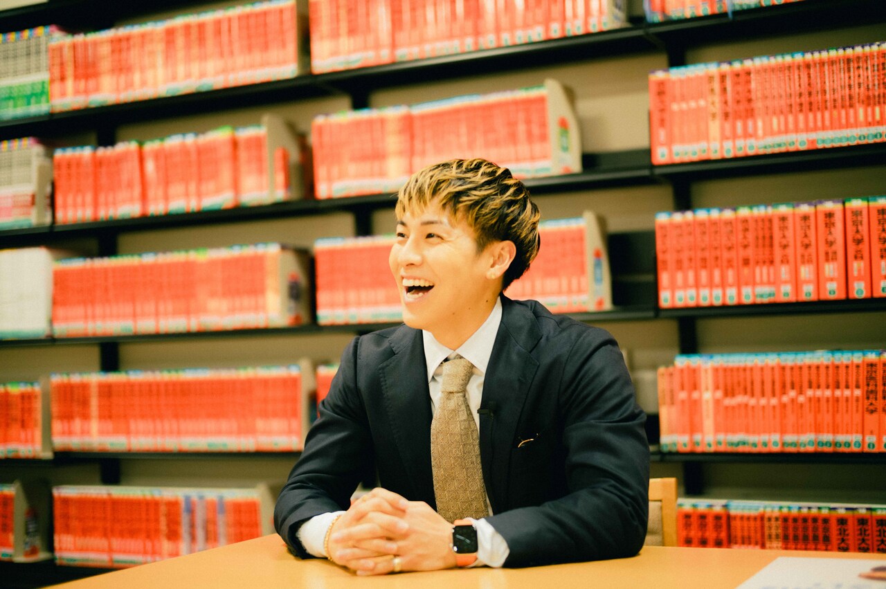 赤本がずらりと並ぶ本棚の前で。