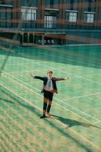 母校をバックに撮影するRIKU。