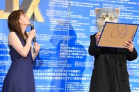 「劇場版ラジエーションハウス」の主題歌「More Than Words」に込めた思いをホワイトボードに書くMAN WITH A MISSIONのKamikaze Boy（右）とそれを覗き込む本田翼（左）。