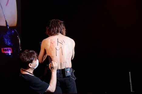 スタッフにさまざまな言葉をマジックで体に書き込まれる鬼龍院翔。