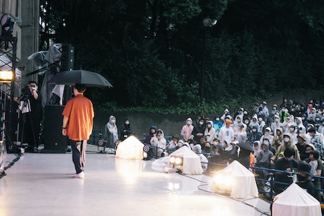傘をさしてステージ上をそぞろ歩く高城晶平（Vo, Flute, G）。（撮影：廣田達也）