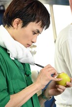 りんごにゾウの名前を彫り入れるタクヤ。