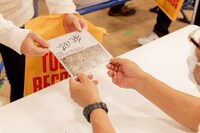 サイン入りの特典をファンに手渡す植松伸夫。