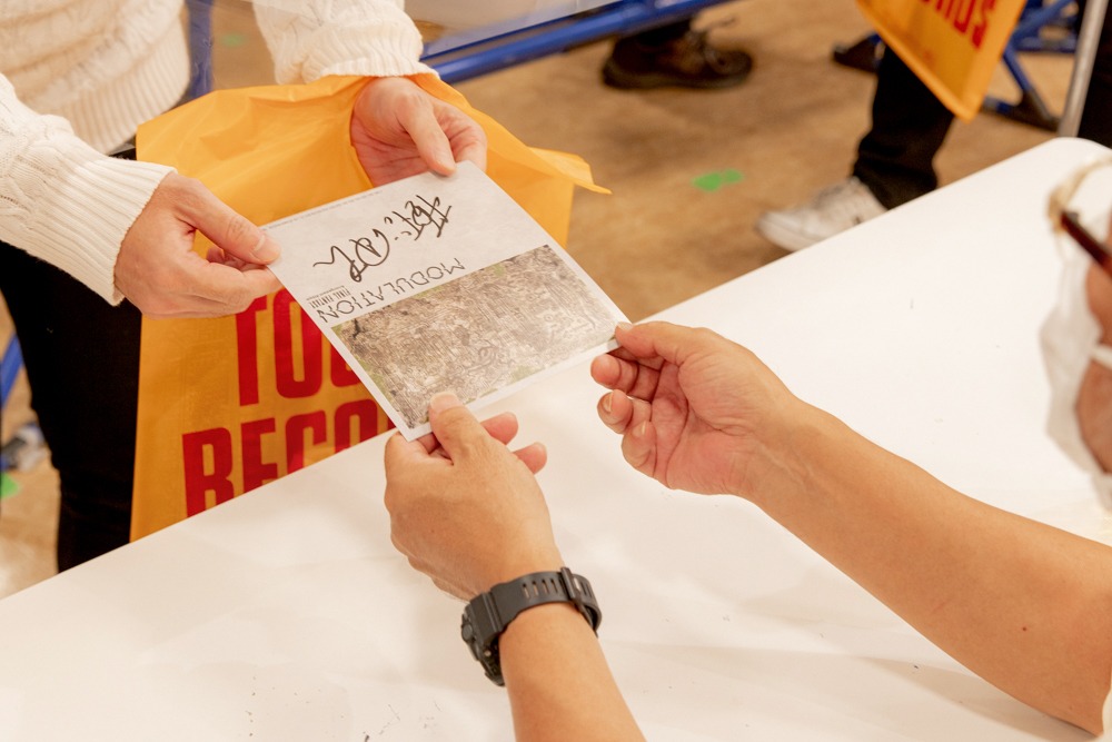 サイン入りの特典をファンに手渡す植松伸夫。