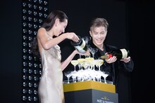 シャンパンをグラスのタワーに注ぎ入れる水原希子（左）、岩田剛典（右）。