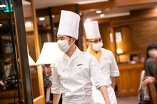 客席を回る料理長姿の藤井隆と、ロイヤルホストの水野孝哉スーパーバイザー。