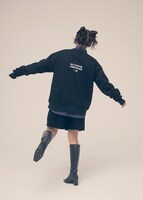 「NO COFFEE × FIRSTORDER CREW SWEAT SHIRTS（BLACK）」のバックプリントを見せる鈴木愛理。