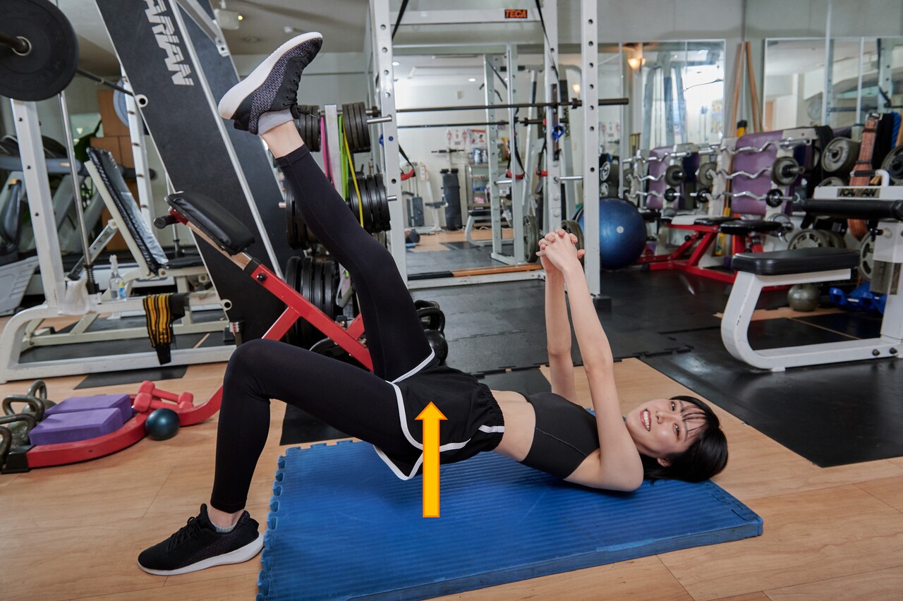 脚とお尻と上げた状態を保ちつつ、カメラに笑顔を見せる隈本茉莉奈さん。