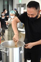 レンズ豆のスープをかきまぜる石濱匡雄。