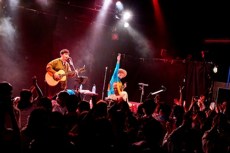 アコースティックギターを弾き終え、ピースサインを掲げる山田義孝（Vo）。（撮影：白石達也）