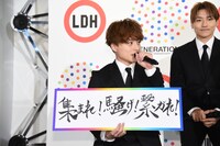 自らの直筆という新スローガン「集まれ！騒げ！繋がれ！」を掲げる白濱亜嵐（左）。