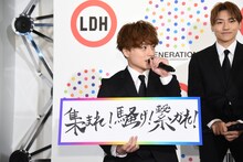 自らの直筆という新スローガン「集まれ！騒げ！繋がれ！」を掲げる白濱亜嵐（左）。