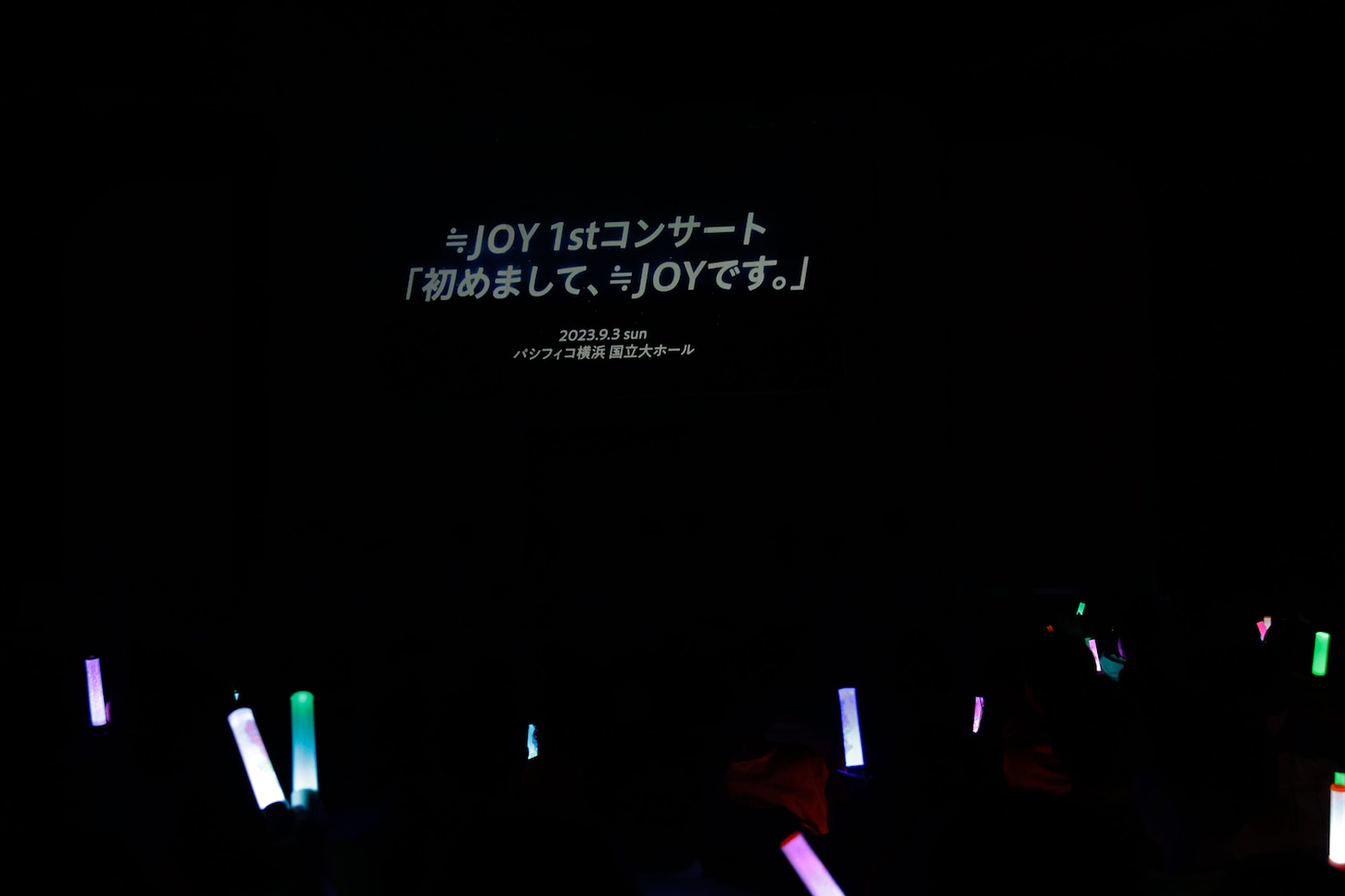 「≒JOY 1stコンサート『初めまして、≒JOYです。』」開催決定の知らせが映し出される会場のスクリーン。