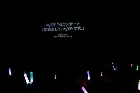 「≒JOY 1stコンサート『初めまして、≒JOYです。』」開催決定の知らせが映し出される会場のスクリーン。
