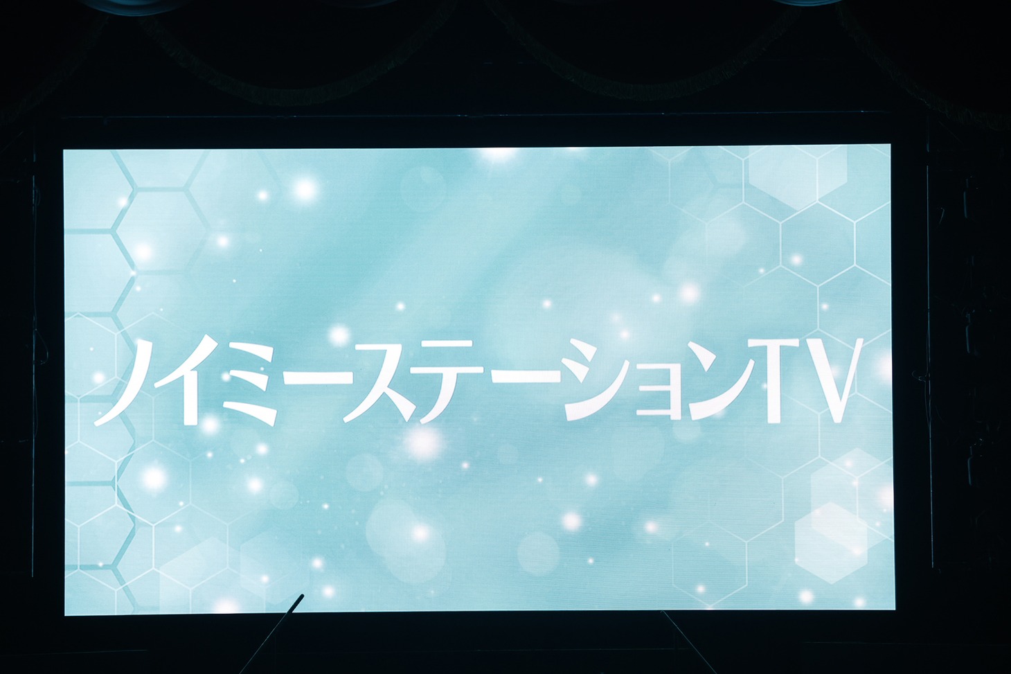 「ノイミーステーションTV」放送決定の知らせが映し出される会場のスクリーン。(c)YOANI