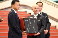 中野サンプラザの金野晃代表取締役会長（右）から野村不動産の松尾大作代表取締役社長（左）に贈呈されたサイン入りの中野サンプラザの椅子。