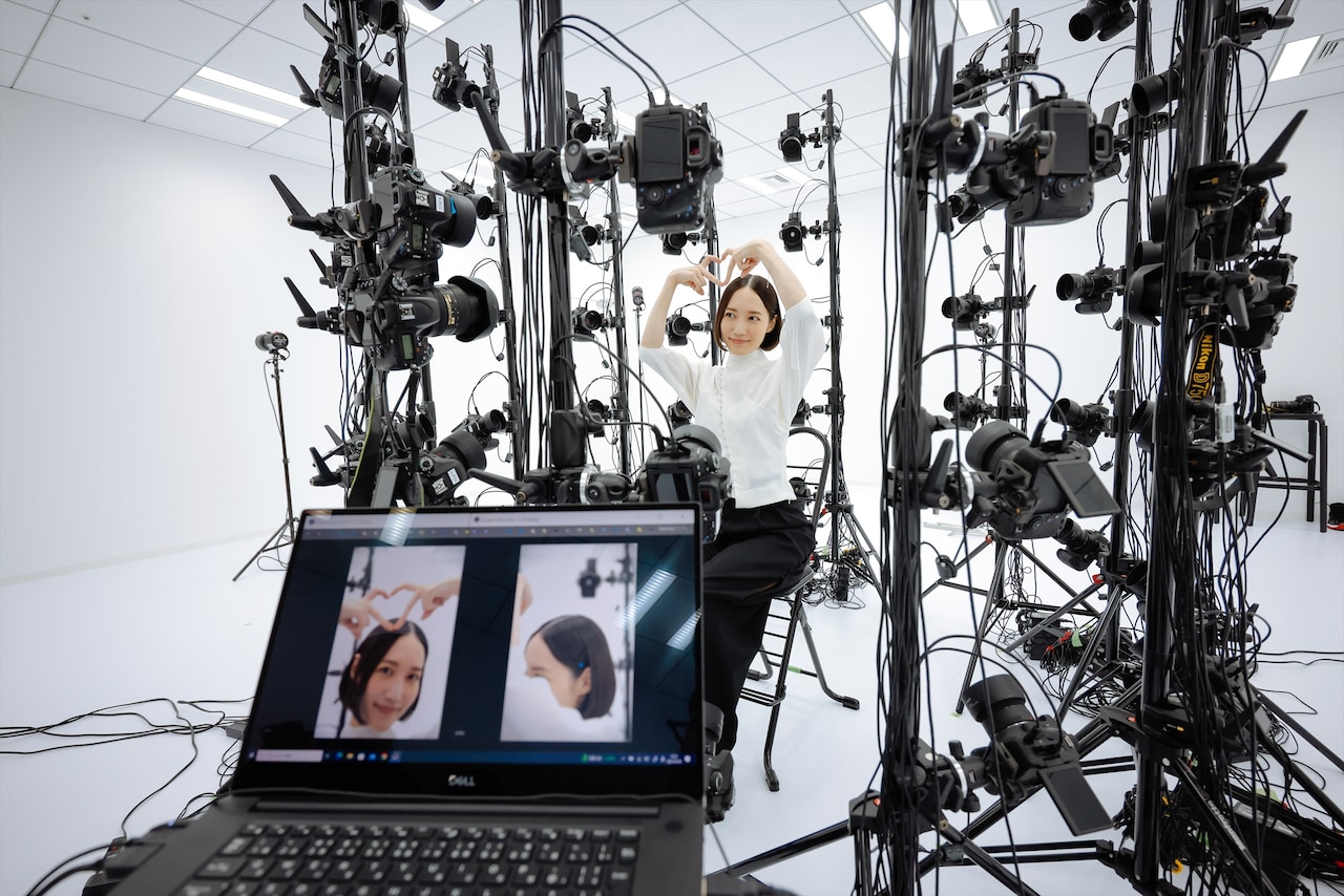 3Dスキャン用カメラに向かって指ハートをするのっちさん。