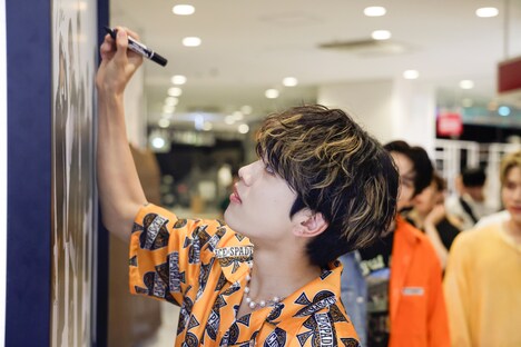 真剣な表情でサインを書く平本健。