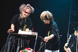 ケーキを運び込む柩(G / NIGHTMARE)、ミヤ(G / MUCC)。(撮影:冨田味我)