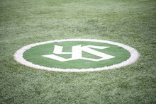 人工芝に東京ヤクルトスワローズの球団マークが刻まれた明治神宮野球場のネクストバッターズサークル。