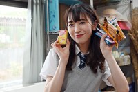 手にいっぱい駄菓子を持ち、笑顔を浮かべる小泉遥香。