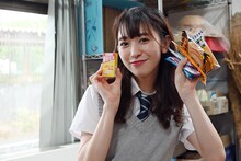 手にいっぱい駄菓子を持ち、笑顔を浮かべる小泉遥香。