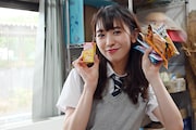 手にいっぱい駄菓子を持ち、笑顔を浮かべる小泉遥香。