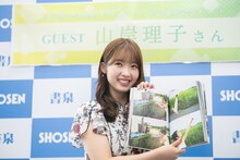 1st写真集と同じロケーションのさとうきび畑で撮影したカットを見せる山岸理子（つばきファクトリー）。